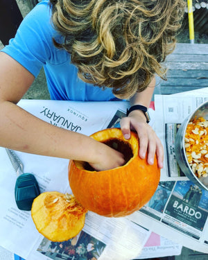 A child taking the seeds out of a pumpkin.