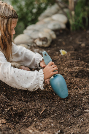 Photo of a young girl with long hair and braided headband using a Rutabaga Garden Tool scoop to dig in some fresh soil.