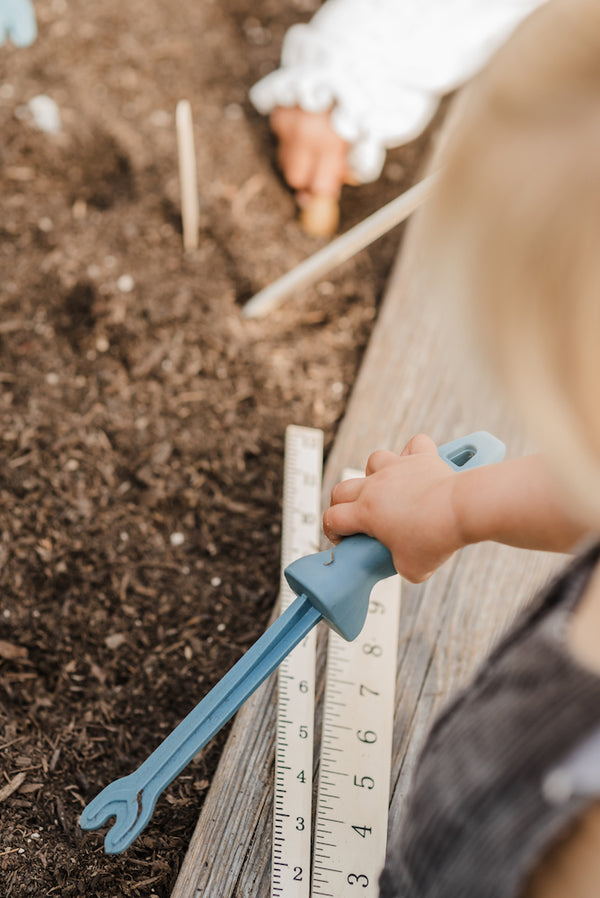A small child gripping the handle of the Rurabaga Garden Tool weed remover.
