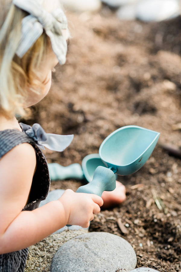 A small child holding a Rutabaga Garden Tool Scoop.