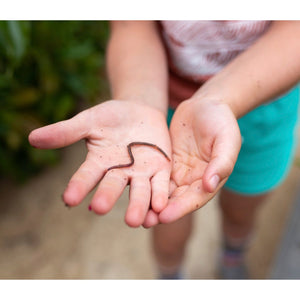 A girl with an earthworm in her hand.