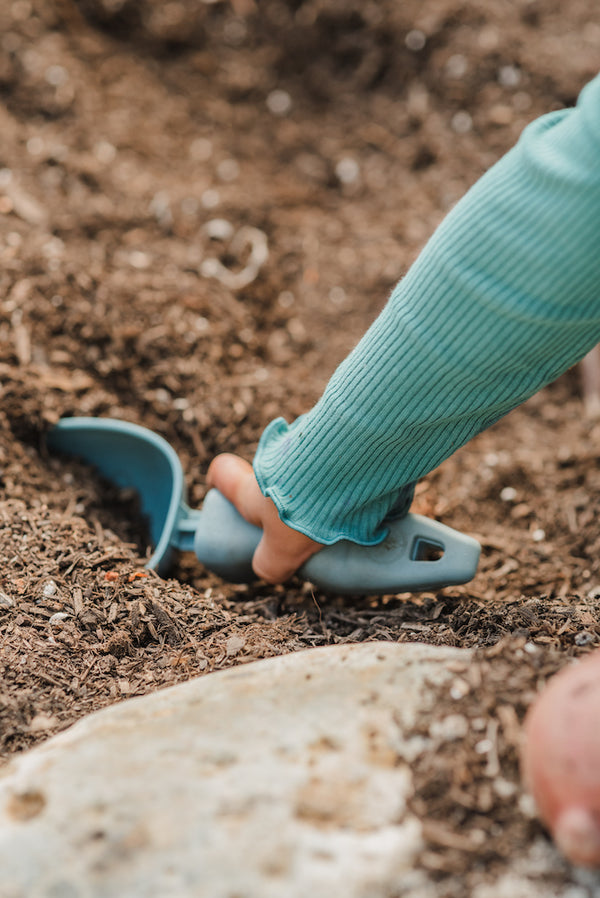 A child digging with the scoop into the soil.