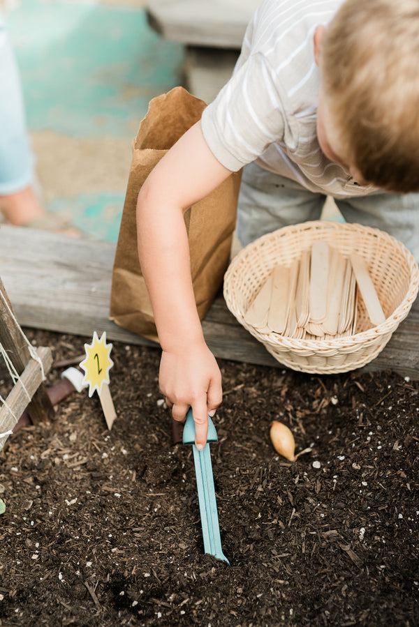 A young boy using the Rutabaga Weed Remover in a garden bed.